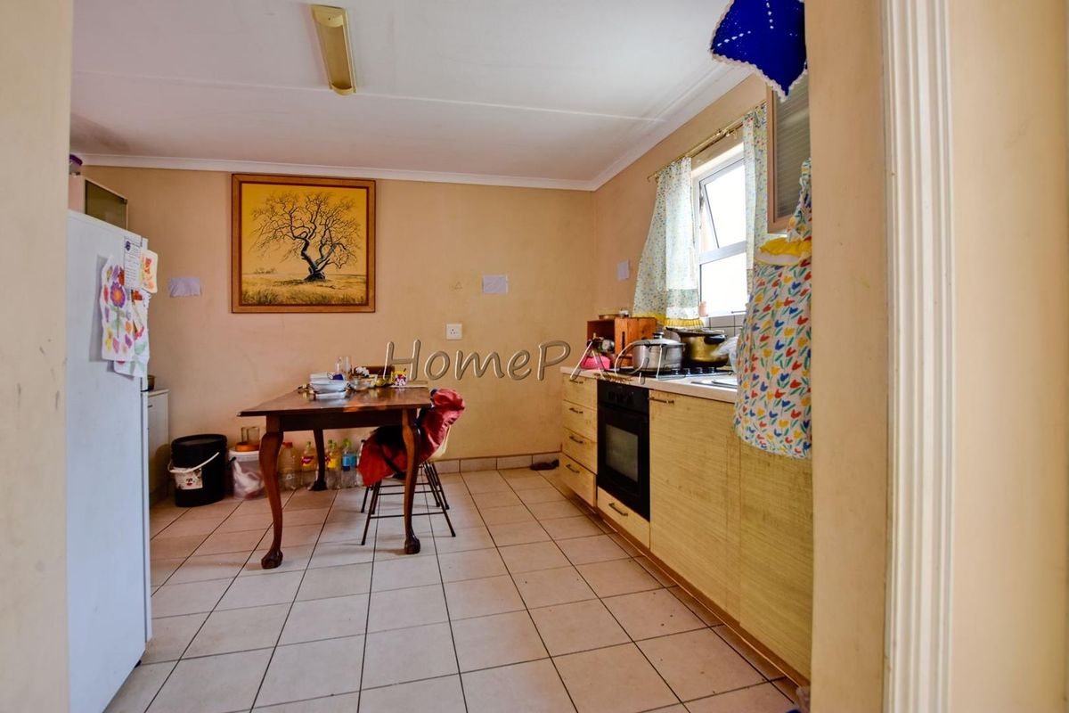 A functional kitchen area featuring built-in cabinetry, an integrated oven and hob, and tiled flooring, requiring cosmetic updates to improve its overall condition.