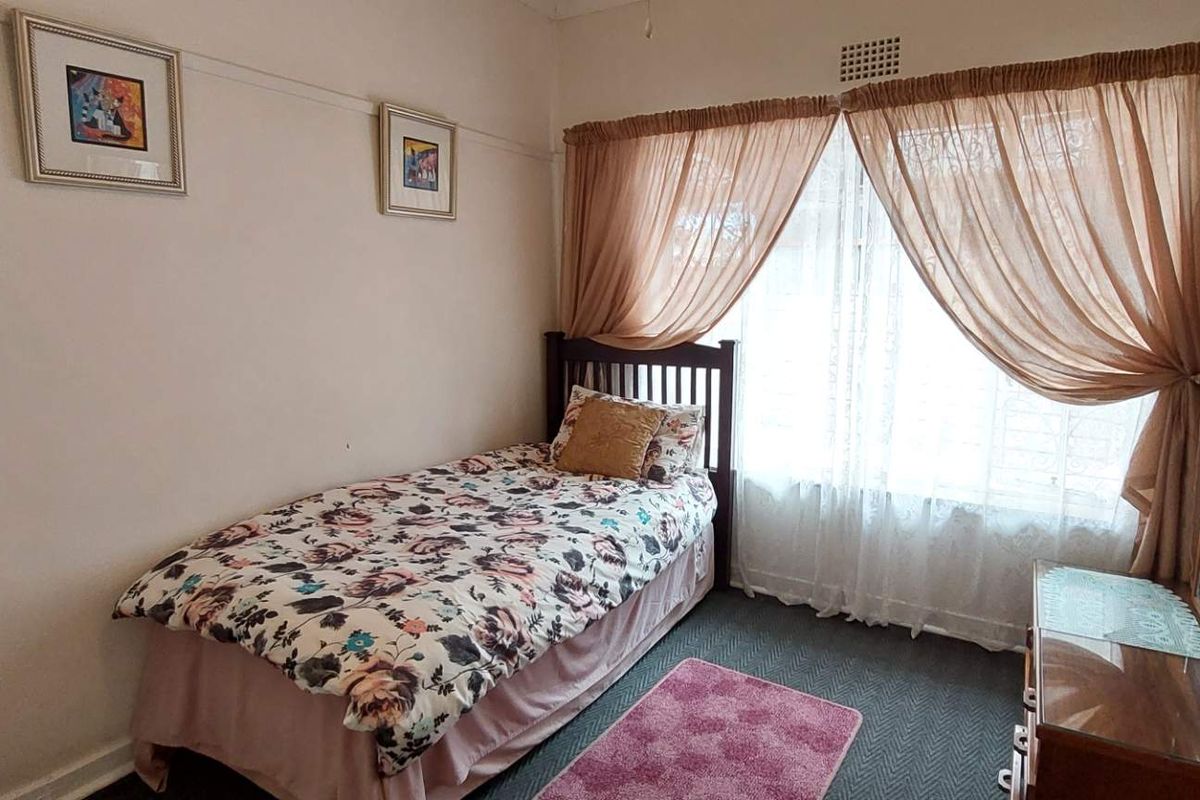 A functional bedroom featuring carpeted flooring, a large window with curtains, and picture rail molding.