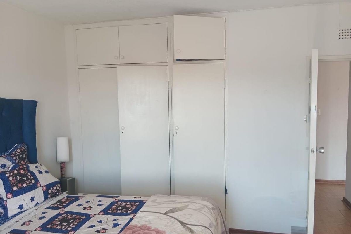 A bedroom featuring white built-in cupboards with overhead storage units, providing ample storage space.