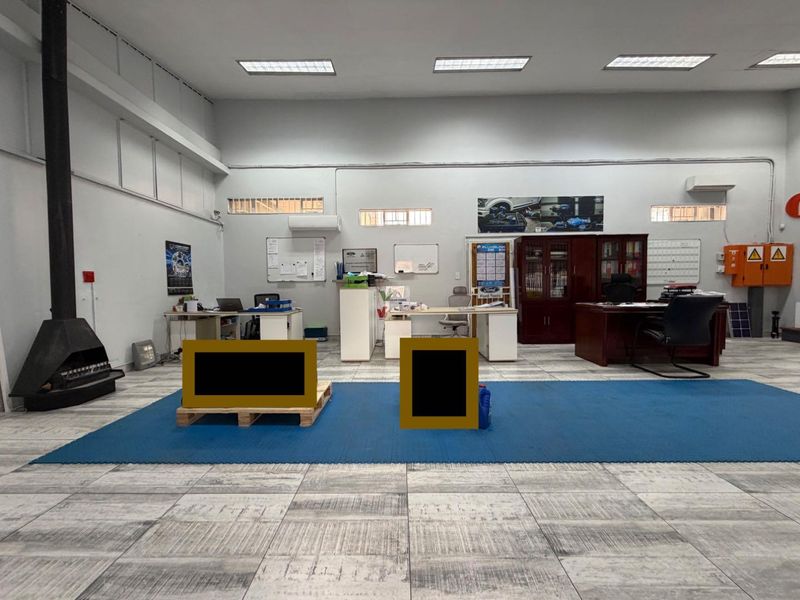 A spacious office area featuring tiled flooring, recessed lighting, and a wall-mounted air conditioning unit, suitable for a professional business environment.