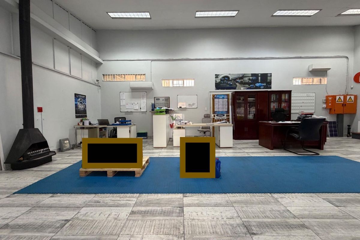 A spacious office area featuring tiled flooring, recessed lighting, and a wall-mounted air conditioning unit, suitable for a professional business environment.