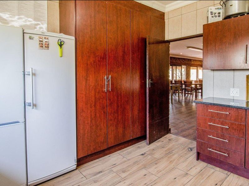A functional kitchen featuring dark wood cabinetry, granite countertops, and tiled flooring, with a direct view into the adjacent dining area.