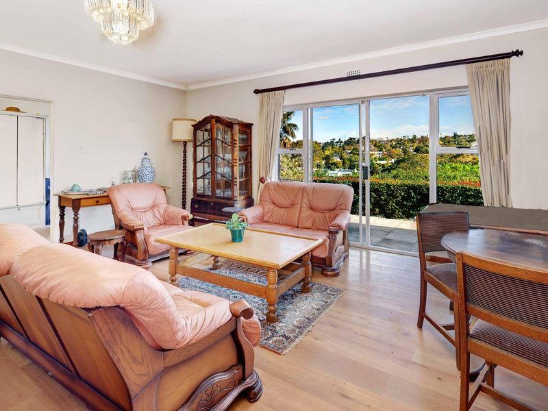 Spacious living room featuring hardwood flooring, a crystal chandelier, and large sliding glass doors that provide natural light and access to the outdoor area.