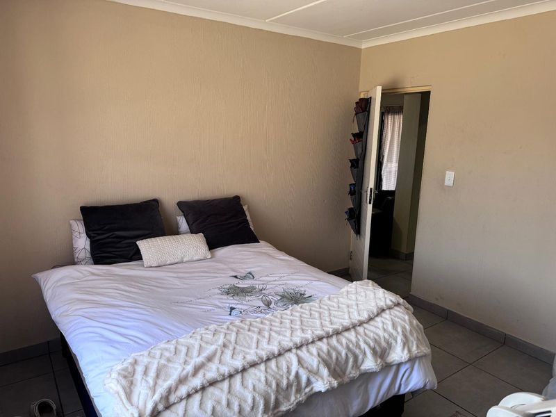 A functional bedroom featuring neutral textured walls and tiled flooring, providing a simple and clean space for rest.