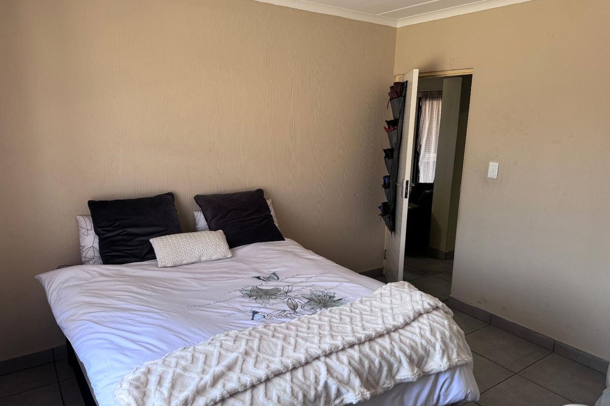 A functional bedroom featuring neutral textured walls and tiled flooring, providing a simple and clean space for rest.