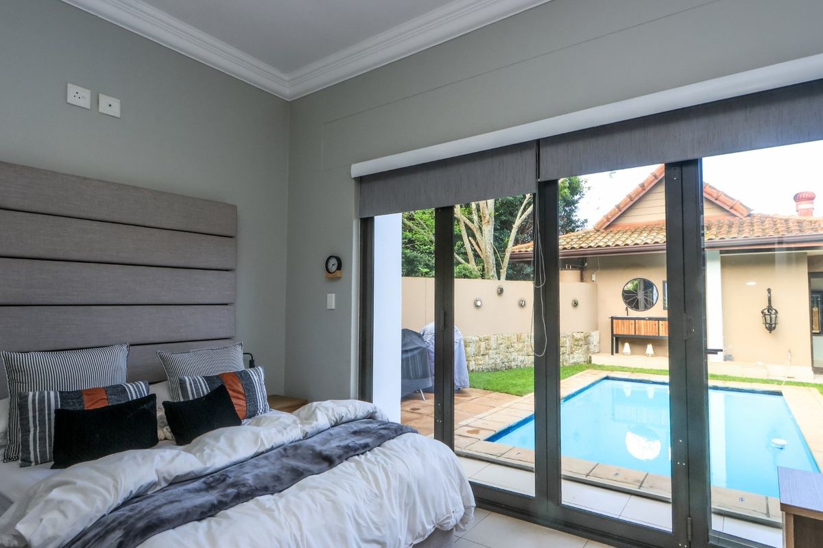 Spacious bedroom featuring a built-in headboard, crown molding, and large sliding glass doors that open directly onto a private pool area.