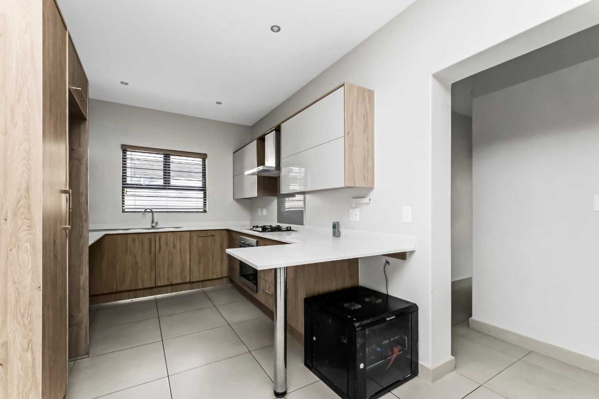 Modern kitchen featuring wood-grain and high-gloss cabinetry, stone countertops, a gas hob, extractor fan, and tiled flooring.