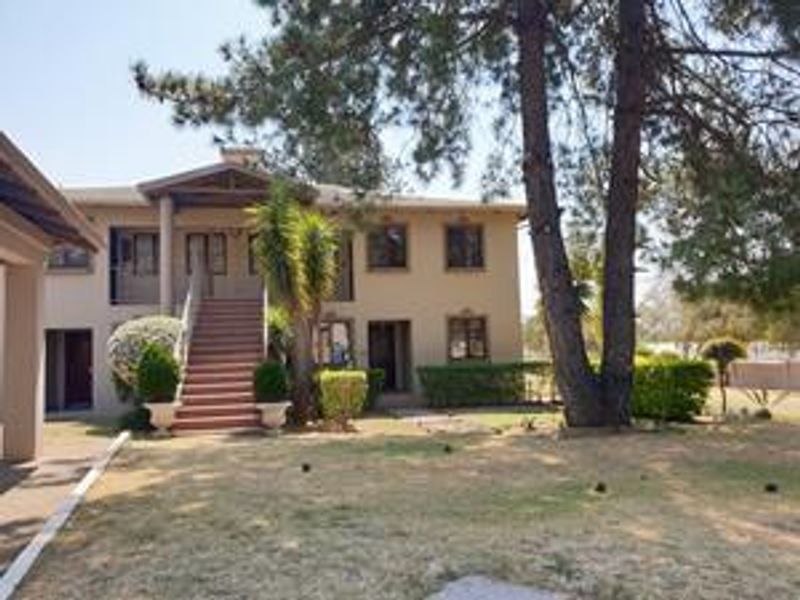 Rear view of the apartment building featuring an external staircase leading to an upper balcony and a spacious garden area with mature trees.