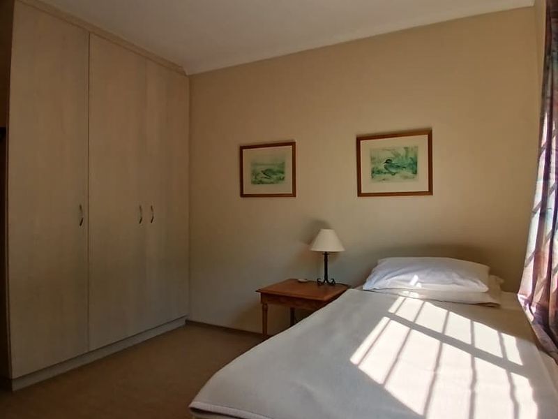 A functional bedroom featuring built-in cupboards, carpeted flooring, and natural light, providing a comfortable and practical living space.