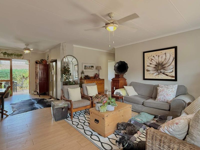 Spacious open-plan living area featuring laminate flooring, ceiling fans, and direct access to an outdoor patio through sliding glass doors.