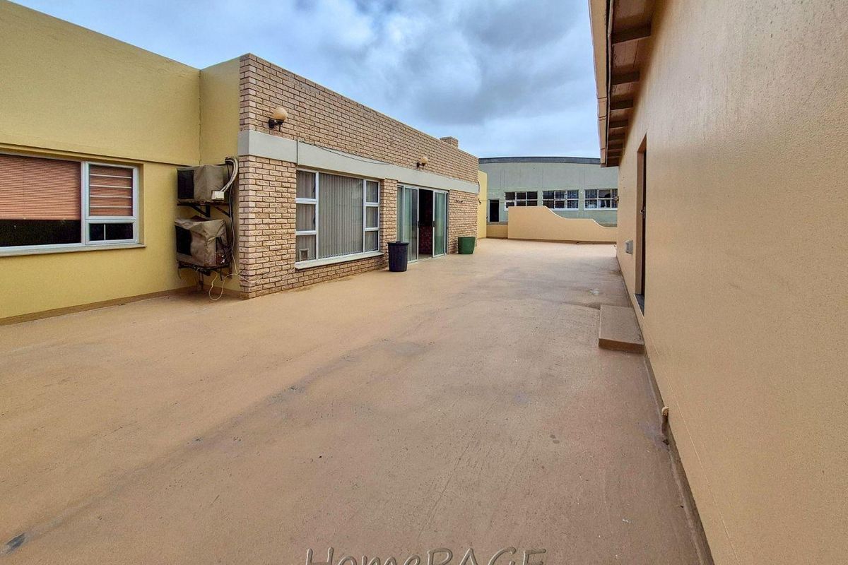 Spacious exterior courtyard area featuring brickwork facade, sliding glass doors, and wall-mounted air conditioning units.