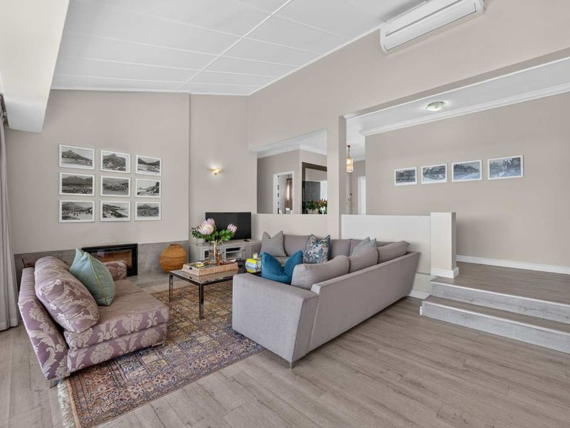 Spacious living room featuring a fireplace, split-system air conditioning, and a raised platform area with modern laminate flooring throughout.