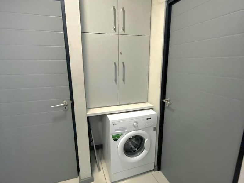A compact laundry area featuring built-in floor-to-ceiling cabinetry and tiled flooring, positioned between two internal doors.