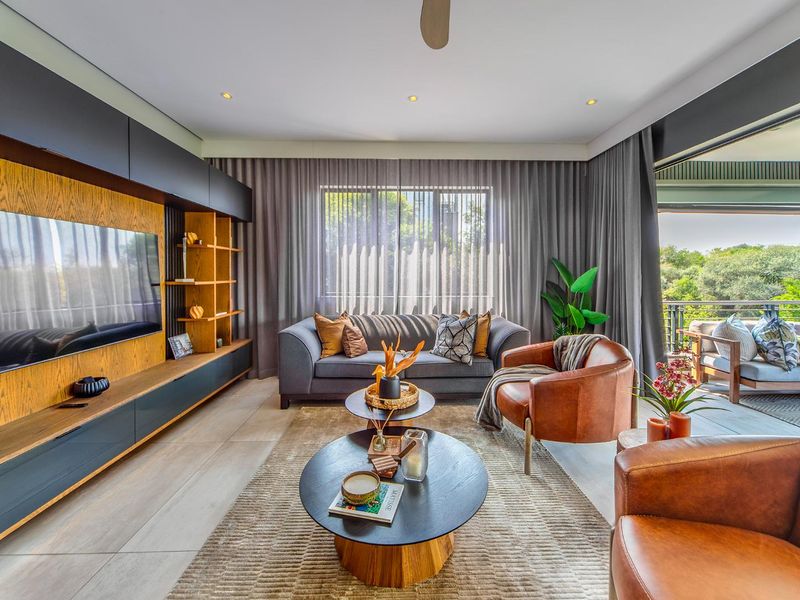 Modern living room featuring a custom built-in media unit, tiled flooring, and large sliding doors that open onto a covered balcony.