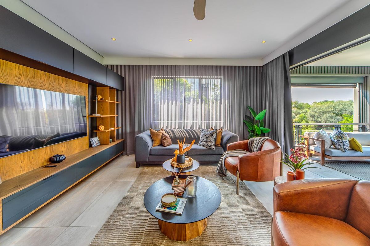 Modern living room featuring a custom built-in media unit, tiled flooring, and large sliding doors that open onto a covered balcony.