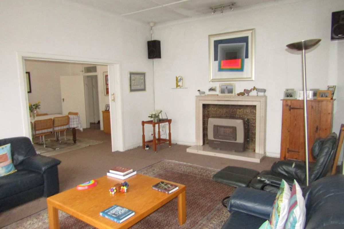 Spacious living room featuring a traditional fireplace with a built-in insert, leading into an adjacent dining area.