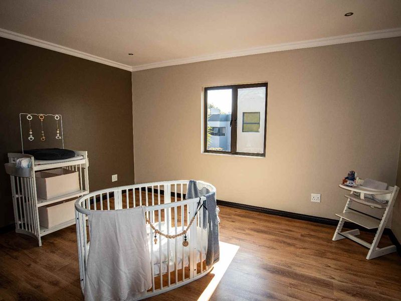 A well-maintained bedroom featuring durable laminate flooring, neutral wall tones, and modern recessed lighting, offering a clean and versatile space.
