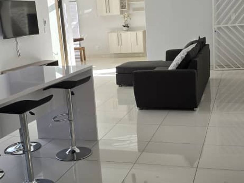Spacious open-plan living area featuring polished floor tiles, recessed lighting, and a modern kitchen with built-in cabinetry and a breakfast bar.