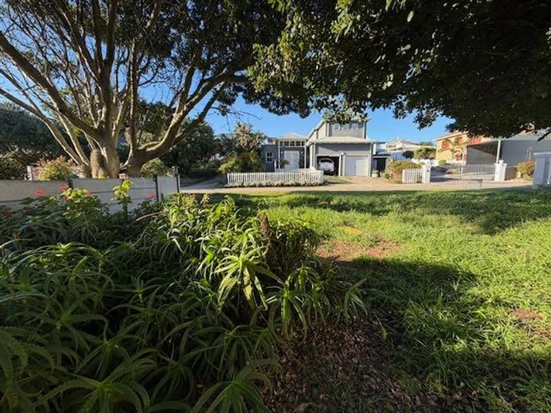 A view of the front exterior of the property, featuring a landscaped garden, picket fence, and driveway leading to the residence.