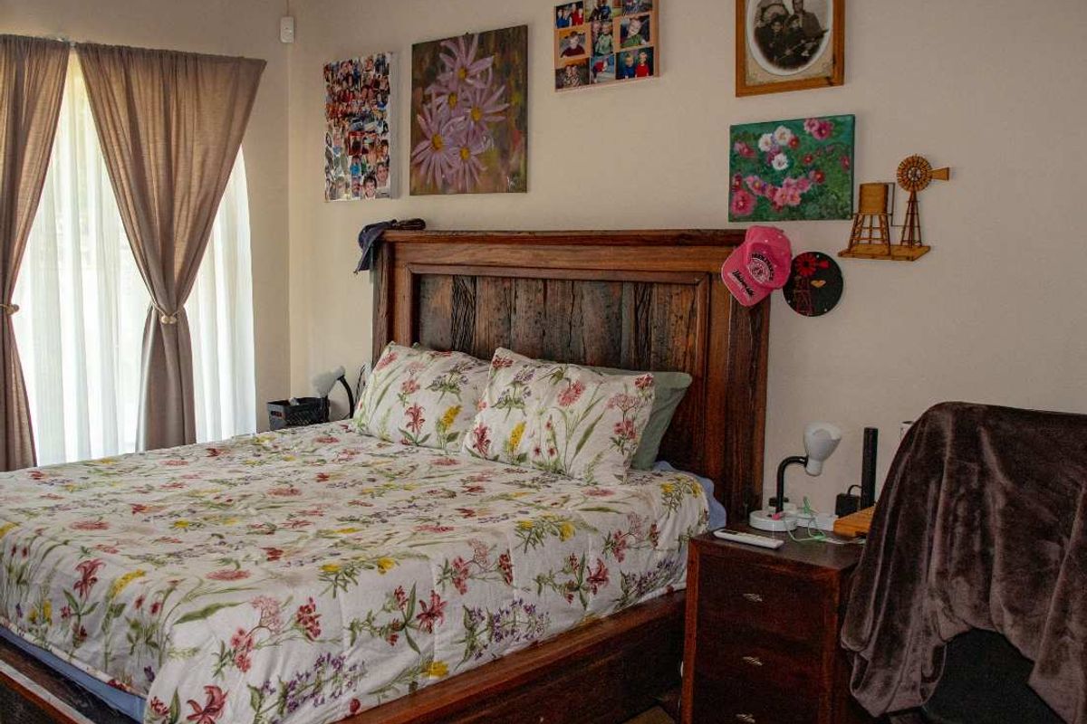 A well-maintained bedroom featuring wood-look flooring, neutral wall finishes, and large windows with curtains, providing a comfortable and functional living space.