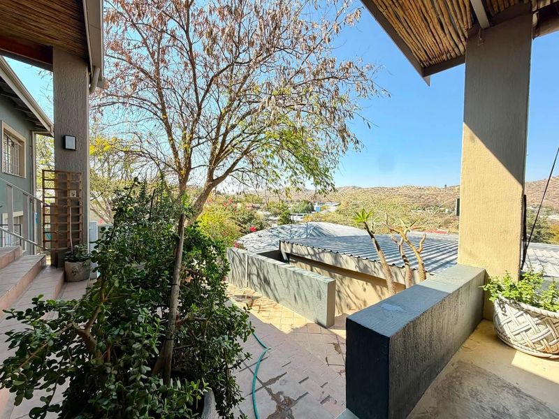A covered outdoor patio area featuring tiled flooring and a masonry balustrade, offering elevated views of the surrounding landscape.