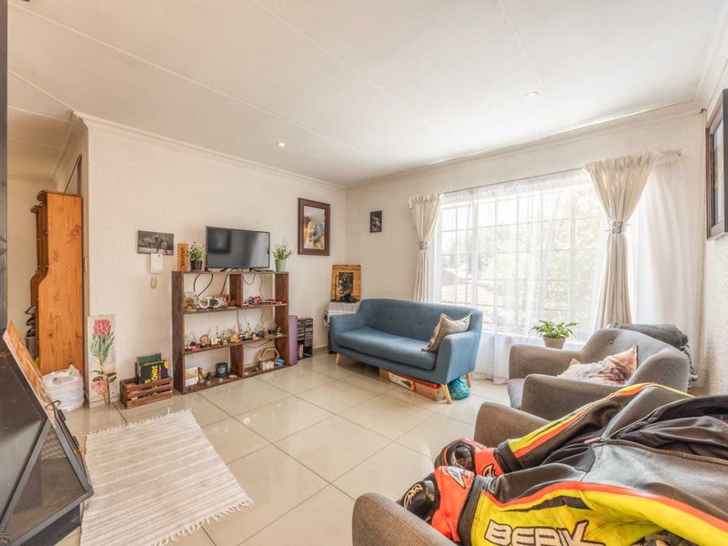 A bright living room featuring large windows, tiled flooring, and a built-in fireplace, offering a comfortable and functional space.