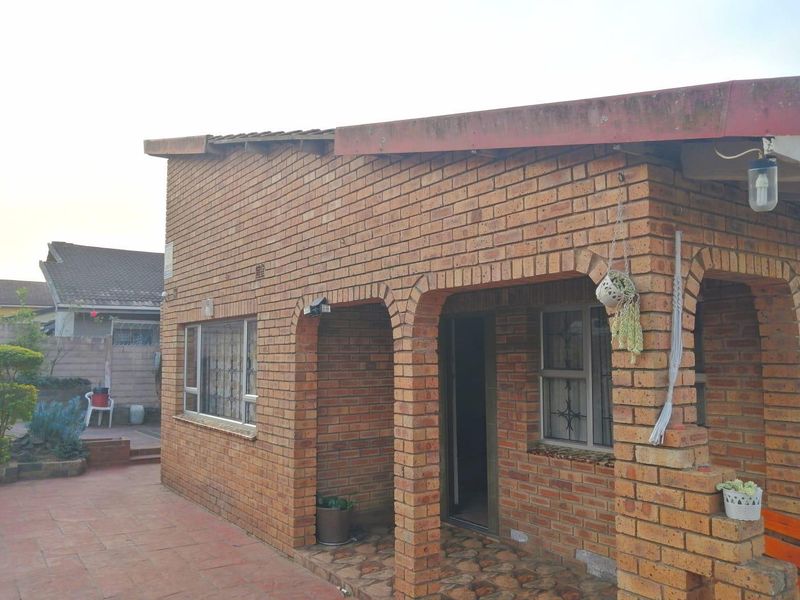 Rear view of a face brick house featuring an arched covered patio area with tiled flooring and security-fitted windows.