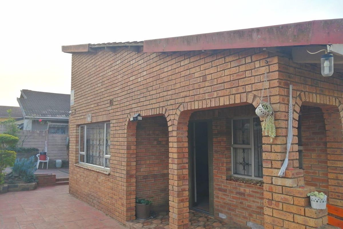 Rear view of a face brick house featuring an arched covered patio area with tiled flooring and security-fitted windows.