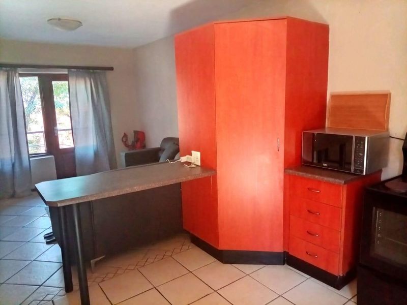 Open plan living area featuring tiled flooring, a breakfast bar, and built-in cabinetry with integrated microwave space.