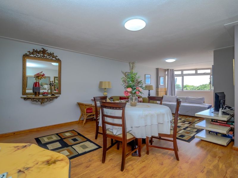 Spacious open-plan living and dining area featuring laminate flooring, neutral wall tones, and large windows providing natural light.