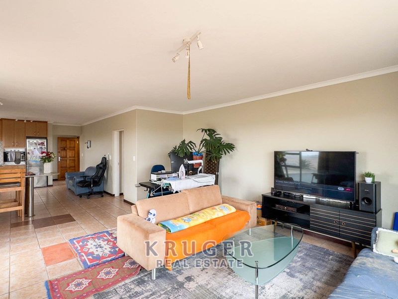Open-plan living area featuring a kitchen with built-in cabinetry, island, and tiled flooring, flowing into a spacious lounge area.
