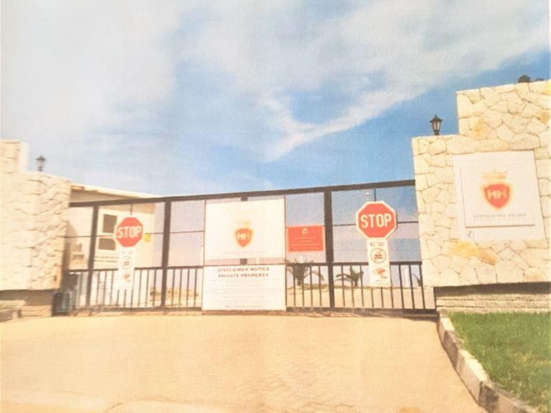 The gated entrance to the residential estate features stone masonry pillars and a secure metal gate, providing controlled access to the property.