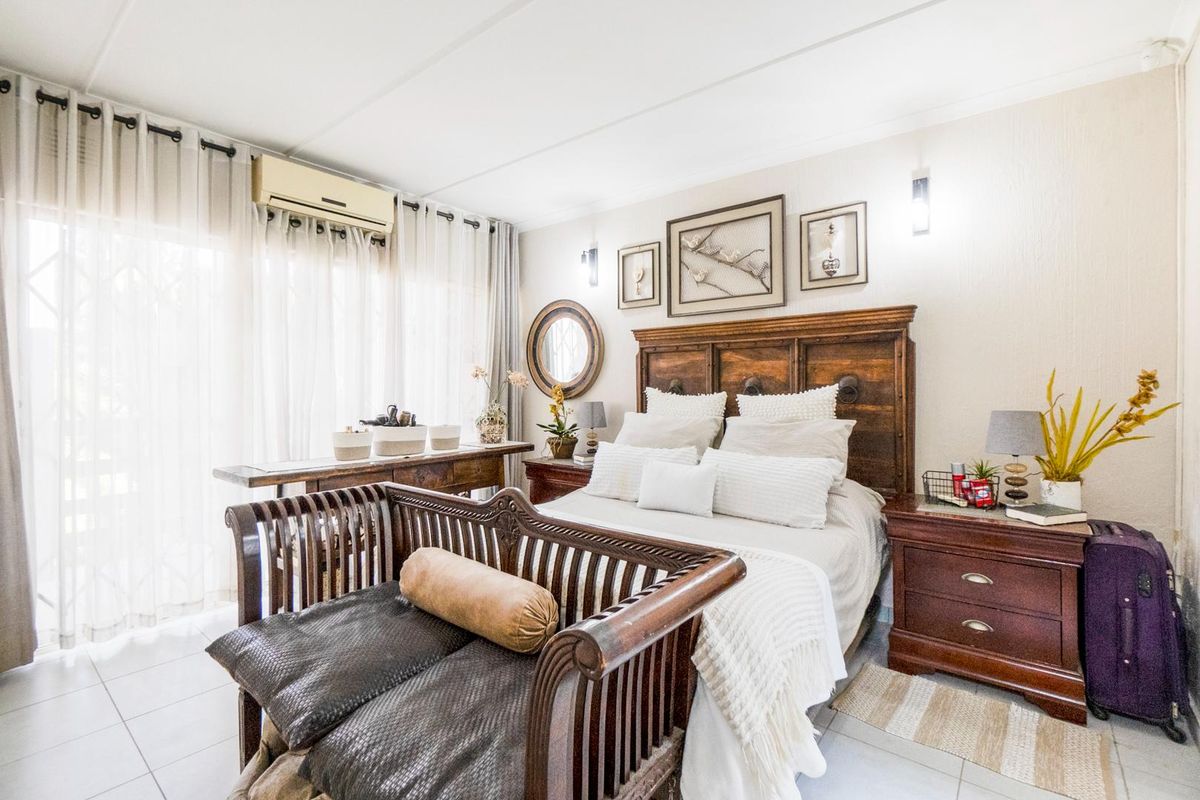 A well-maintained bedroom featuring tiled flooring, wall-mounted air conditioning unit, and sliding glass doors providing access to the exterior.