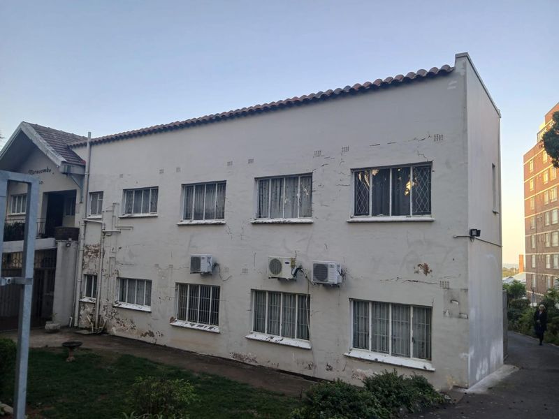 Exterior view of an apartment building facade showing visible plaster cracking, peeling paint, and installed air conditioning units.