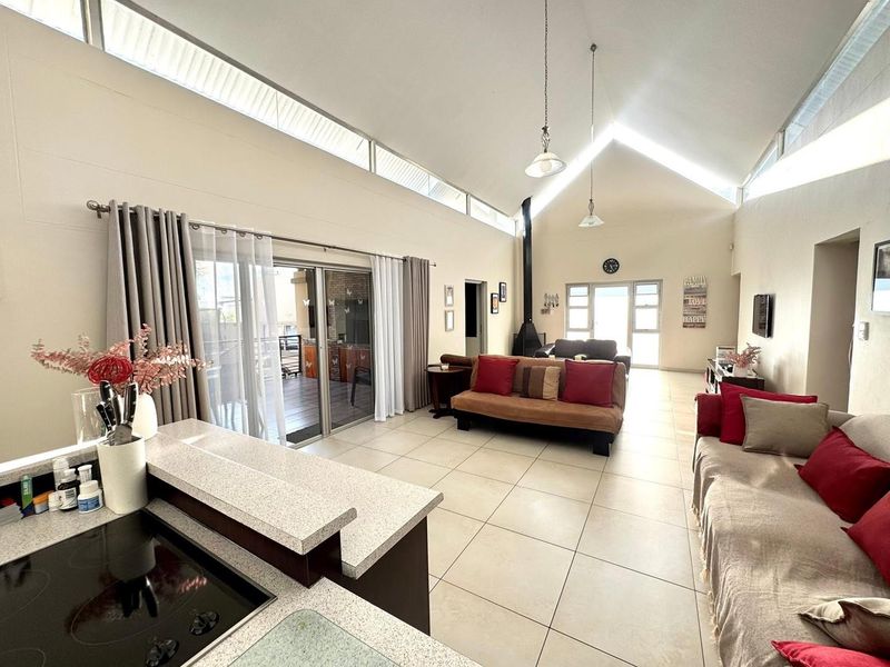Spacious open-plan living area featuring a high vaulted ceiling with clerestory windows, ceramic tile flooring, and a modern freestanding fireplace.