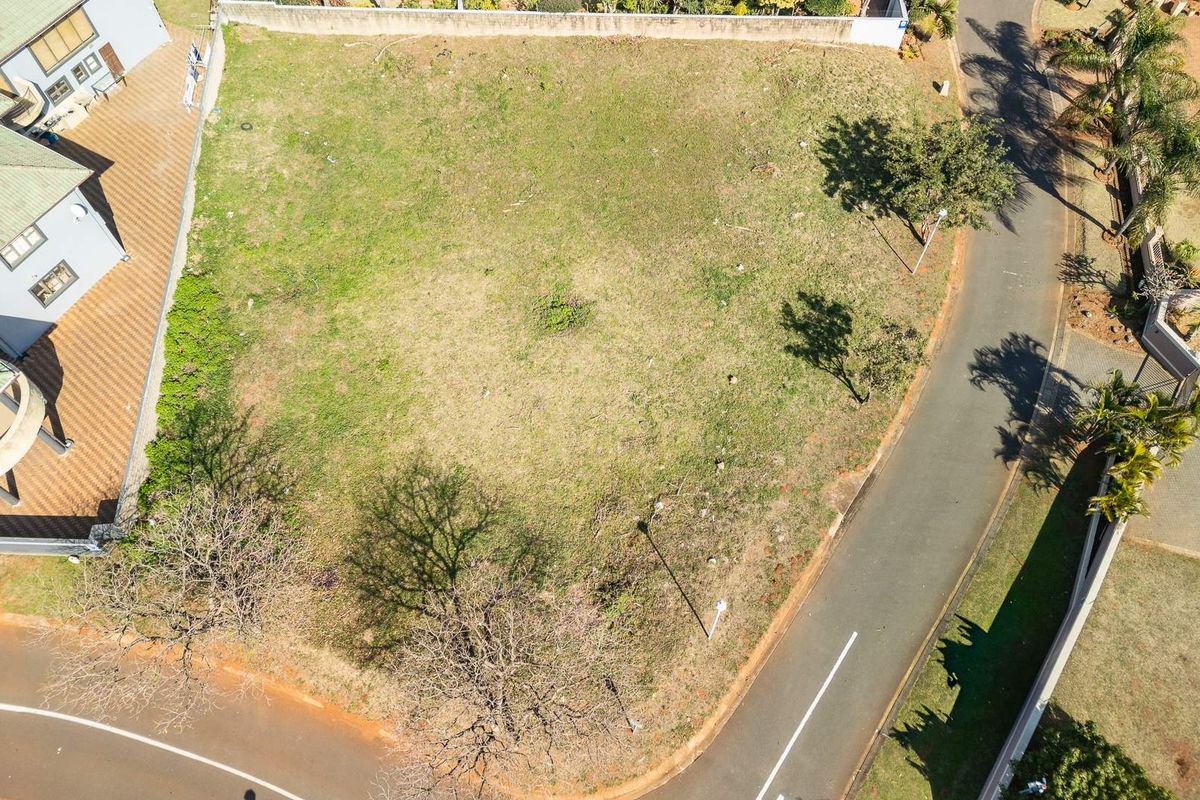 Aerial view of a vacant residential plot situated on a corner lot with established boundary walls and direct road access.