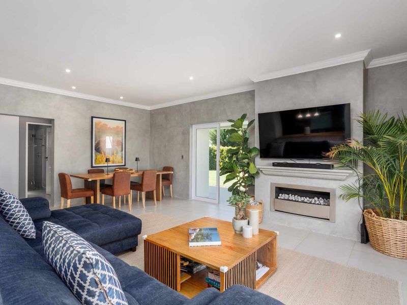 Spacious open-plan living and dining area featuring a modern gas fireplace, sleek concrete-effect wall finishes, and direct access to the outdoor space.