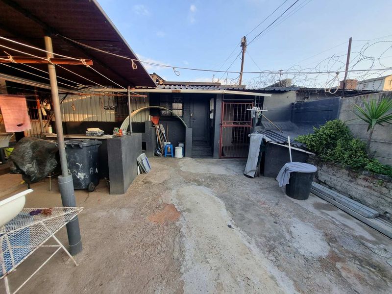 Rear courtyard area featuring a built-in braai, concrete paving, and secure perimeter walling with razor wire.