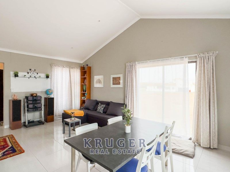 Spacious open-plan living and dining area featuring vaulted ceilings, tiled flooring, and large sliding glass doors providing natural light.