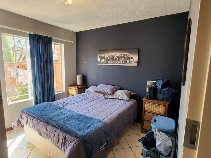 A bedroom featuring tiled flooring and a window, with a dark accent wall providing a focal point for the space.