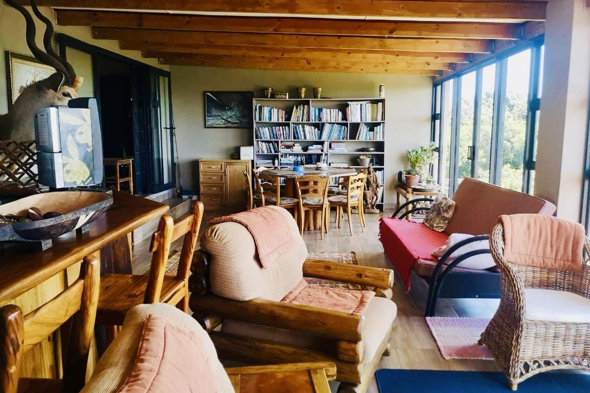 Spacious sunroom featuring exposed timber ceiling beams, large glass windows, and tiled flooring, offering a bright and versatile living space.