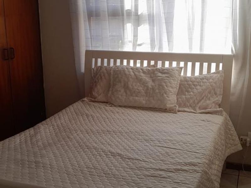 A bedroom featuring tiled flooring and a built-in wooden wardrobe, providing functional storage space.
