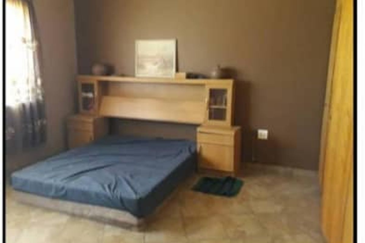 A bedroom featuring tiled flooring and built-in wooden cabinetry, providing a functional and neutral space.
