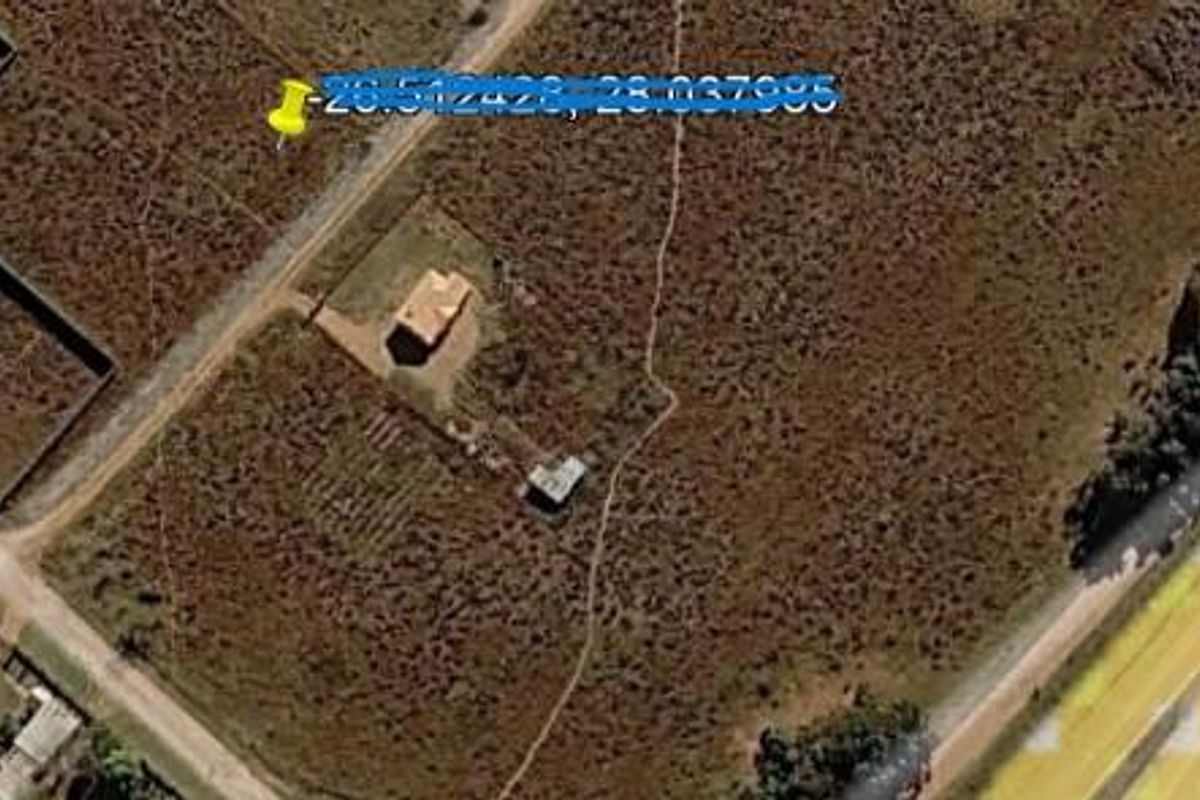 Aerial view of a vacant residential plot featuring existing structures and natural landscape.