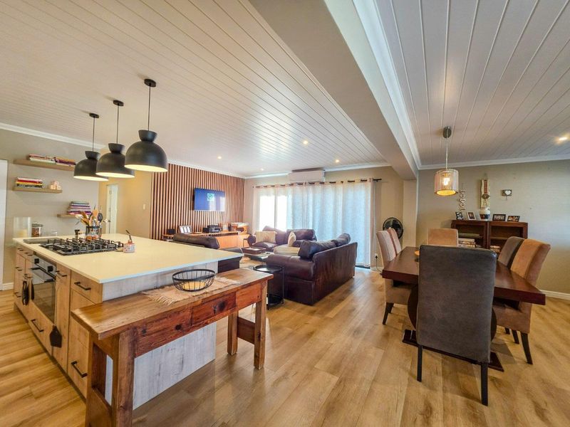 Spacious open-plan living area featuring a modern kitchen with island, timber slat feature wall, and tongue and groove ceilings throughout.