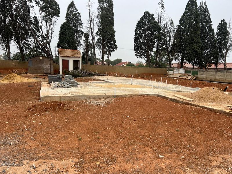 Vacant residential land featuring a concrete slab foundation, perimeter boundary walls, and a small outbuilding, ready for further development.