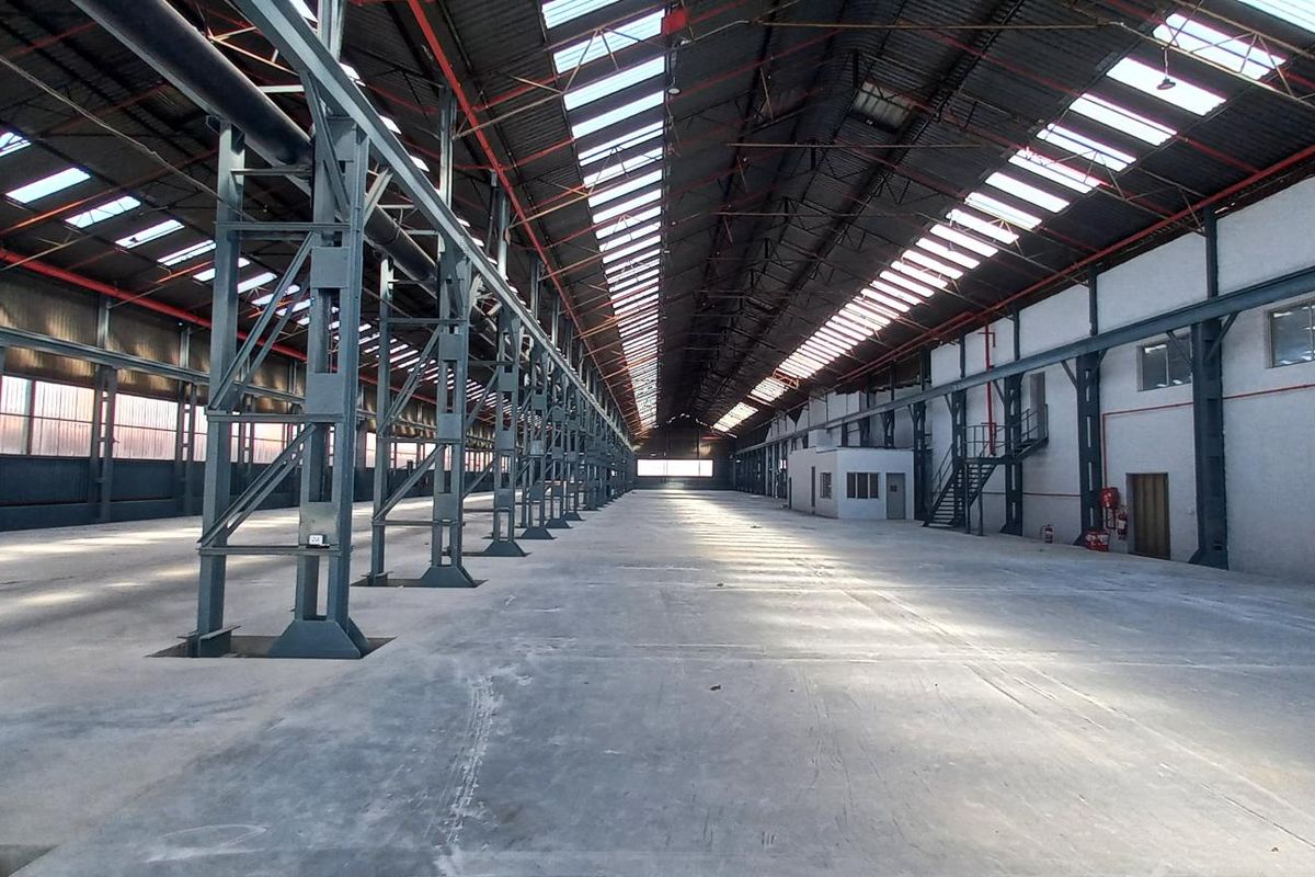 Expansive industrial warehouse space featuring high ceilings, exposed steel portal frame construction, polished concrete flooring, and abundant natural light through integrated roof skylights.