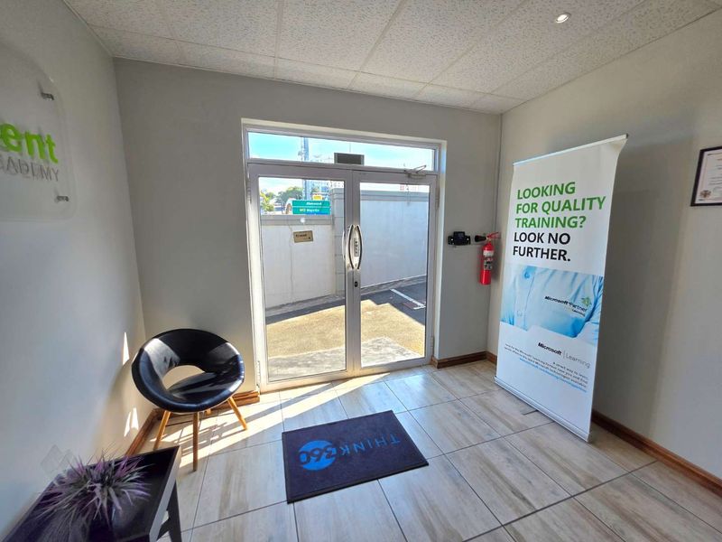 A bright and functional office entrance area featuring tiled flooring, an aluminium glass door, and integrated access control systems.