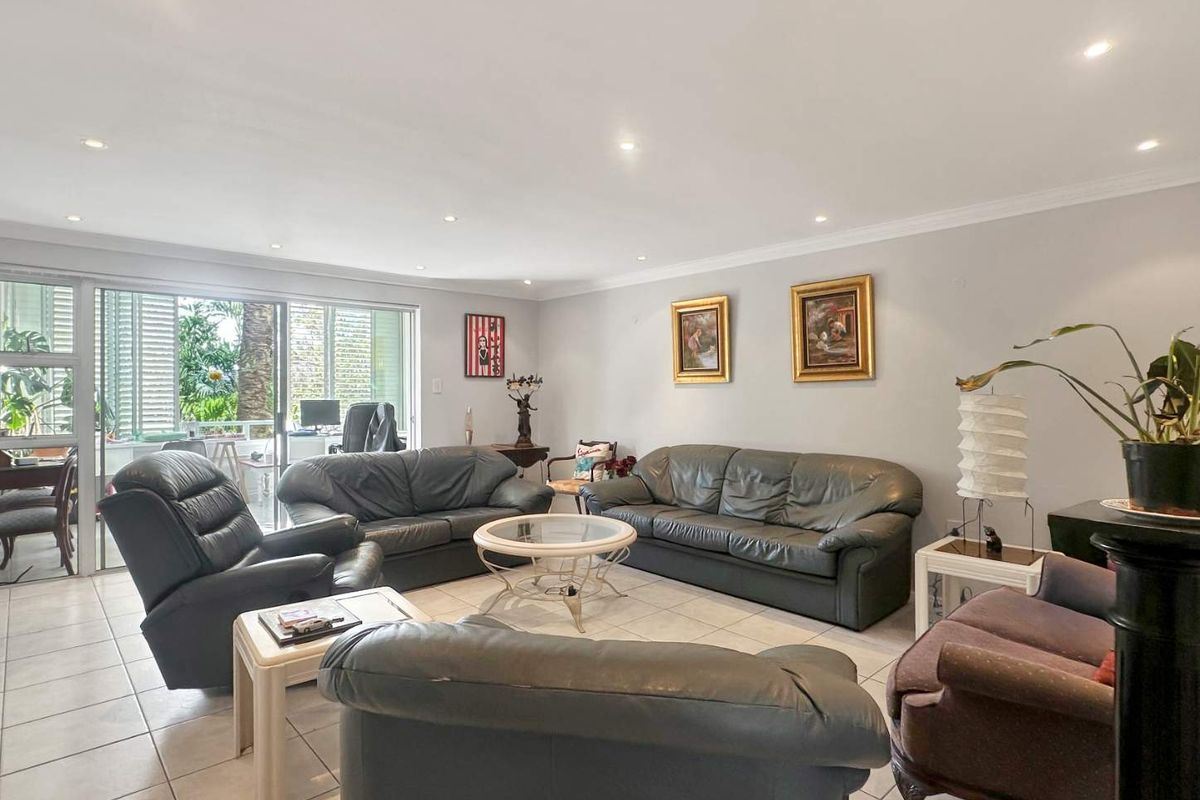 Spacious living room featuring neutral tiled flooring, recessed downlighting, and large sliding glass doors providing access to the outdoor area.
