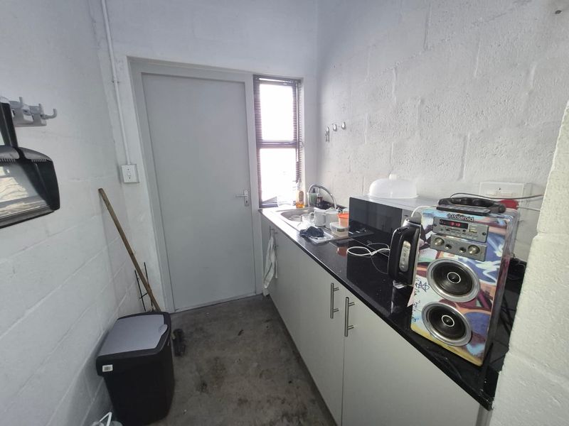 A functional scullery area featuring built-in cabinetry, a sink, and black granite countertops, set against exposed blockwork walls.